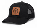 A black trucker-style cap with a brown faux-leather patch on the front featuring a black thorny cross design, set against a plain white background.