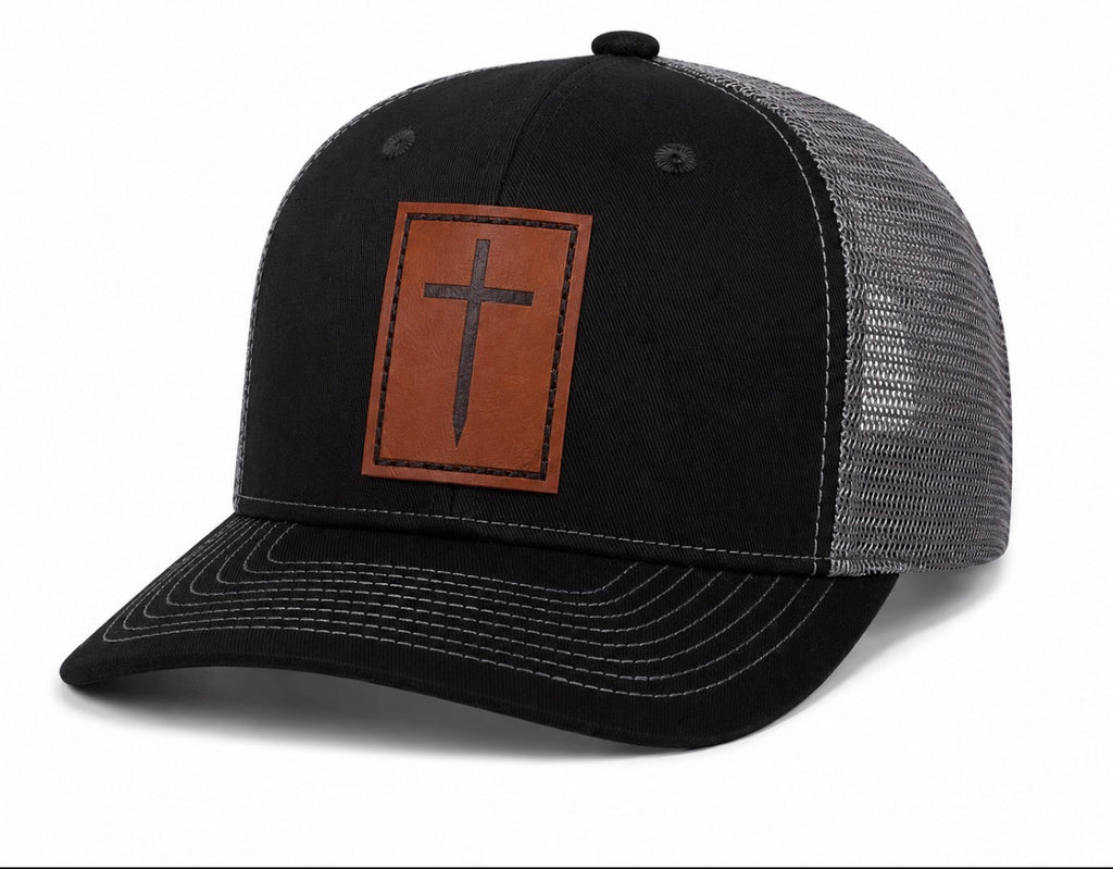 Black and gray trucker hat with brown leather cross patch, angled front view – ETRNL Apparel Cornerstone Hat